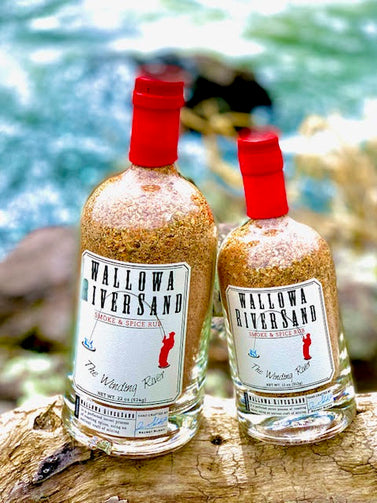 12 oz. bottle and 22 oz. bottle sitting on a log with the Wallowa river in the background